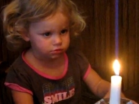 Девочка пытается задуть свечу на торте